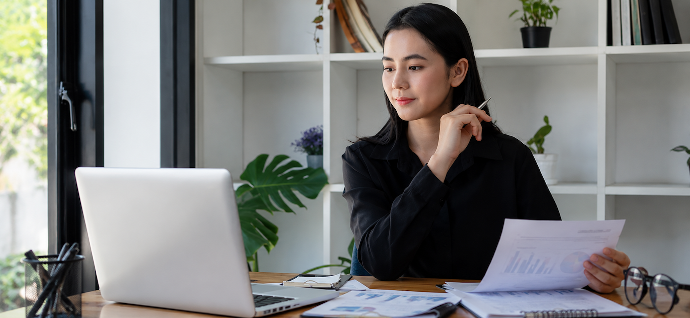Woman looking at document and computer
