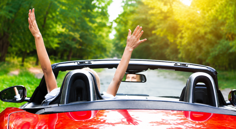 Woman with arms up in a convertible car