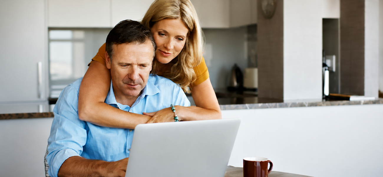 Woman with arm around man while looking at computer
